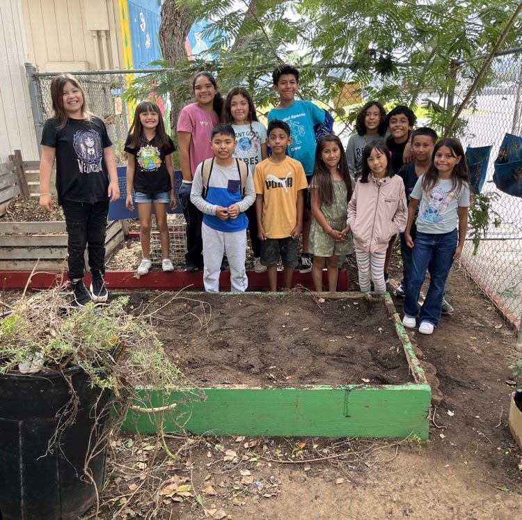 Conway Academy students and staff gathered around a garden bed they built together