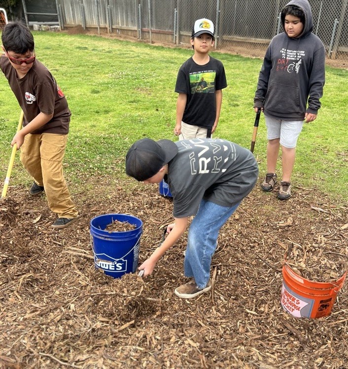 Conway Academy students doing hands-on garden work with buckets and tools