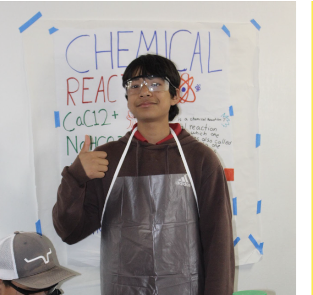 A Hidden Valley Middle School student giving a thumbs up next to a chemical reaction demonstration poster