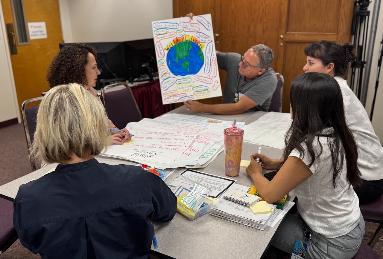 Families reviewing a world map poster with the Design Team